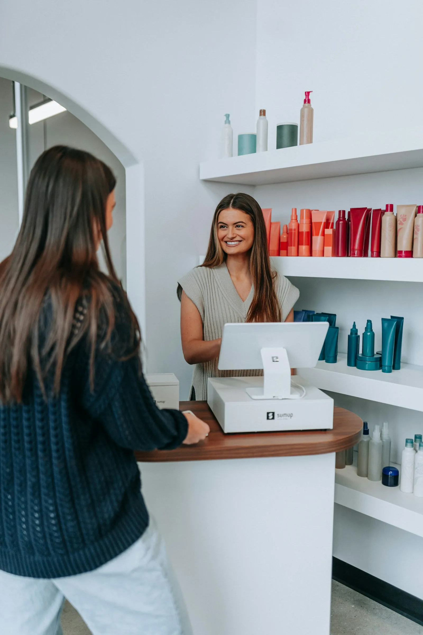 Cliente pagando na recepção de um salão de beleza com maquininha de cartão