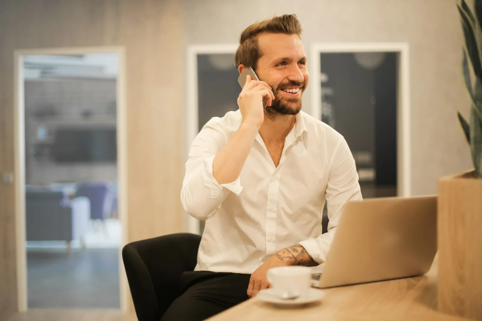 Empreendedor atendendo cliente por telefone enquanto consulta o notebook