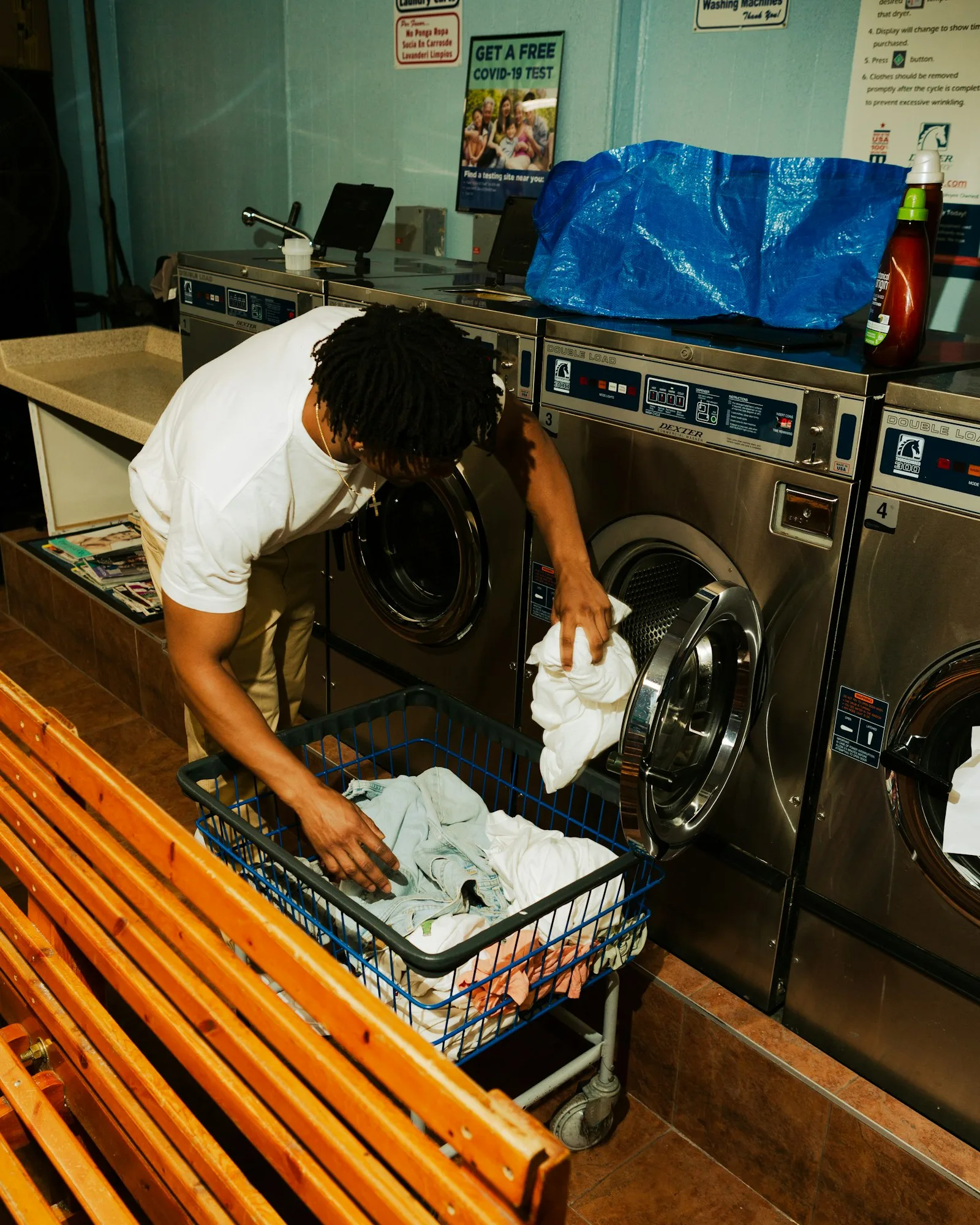 Funcionário de lavanderia organizando roupas na máquina de lavar