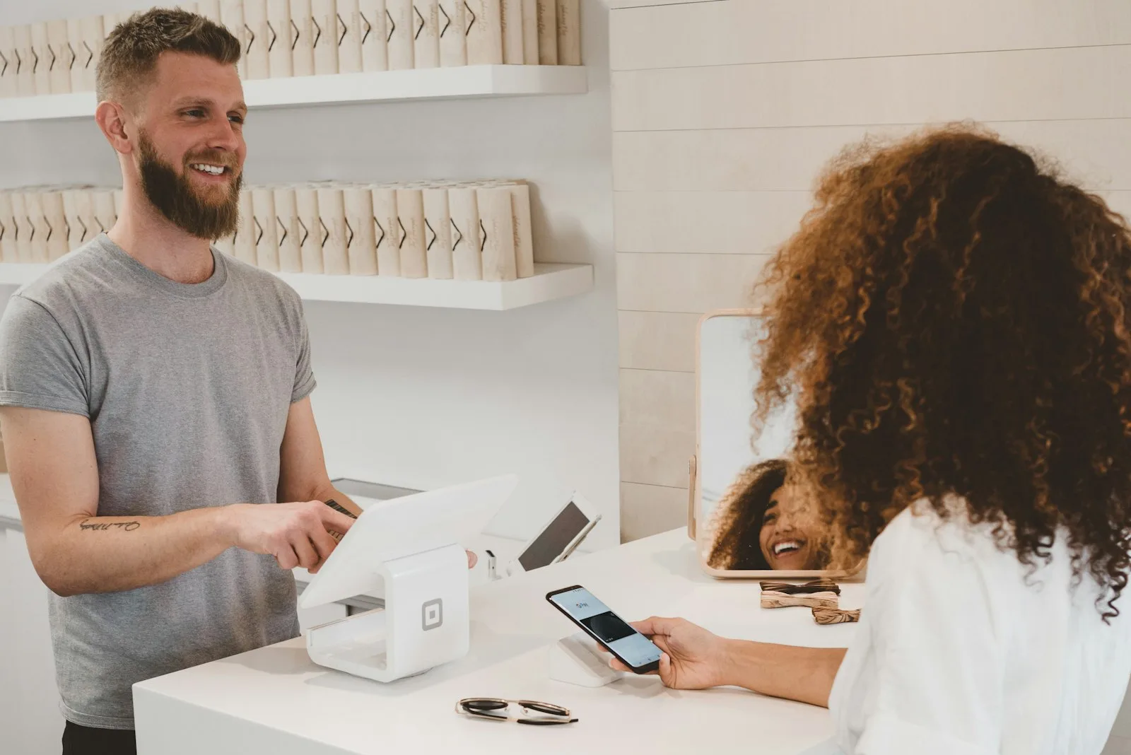 Dono de loja atendendo cliente no balcão com pagamento por aproximação
